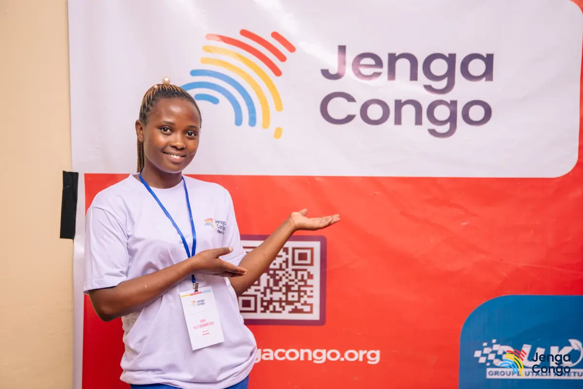 A volunteer welcoming attendees at the Jenga Congo banner